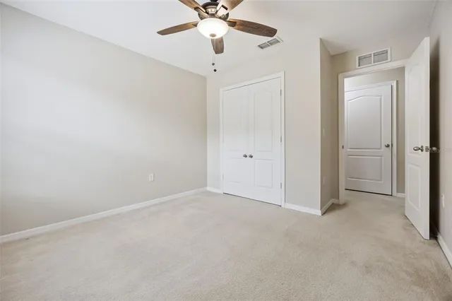 an empty room with a chandelier fan and closet area