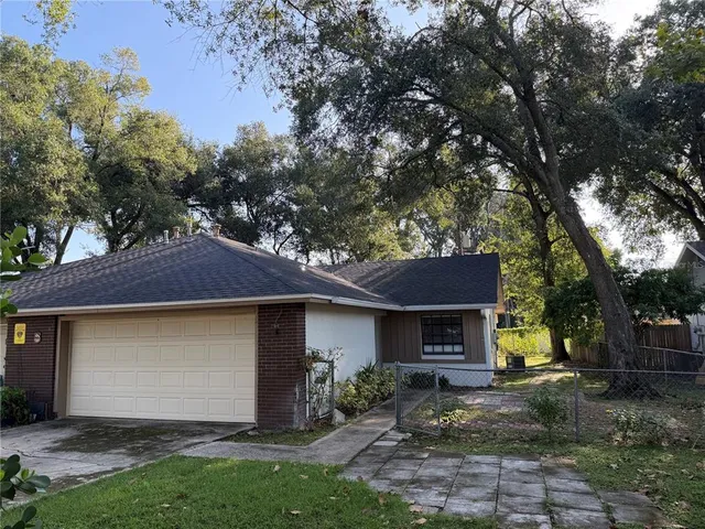 a view of a house with a yard and a large tree