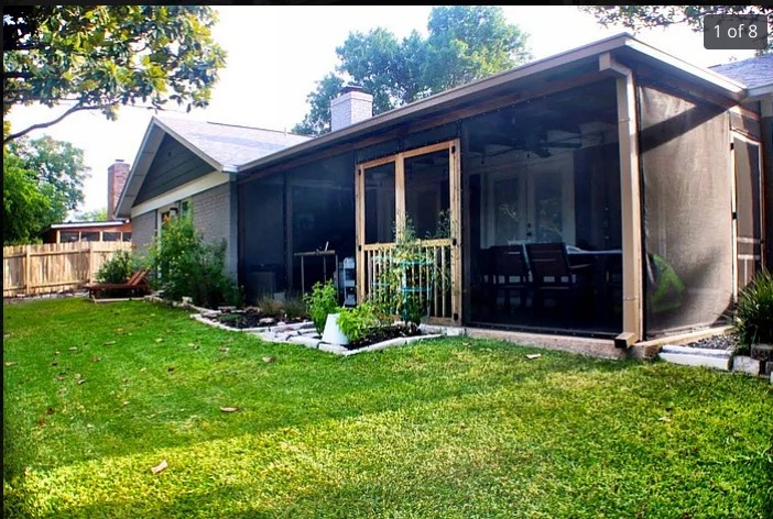 a view of a house with brick walls and a yard with plants