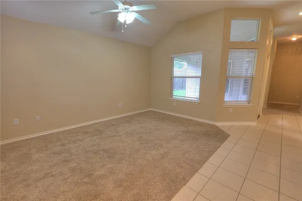 an empty room with chandelier fan and windows