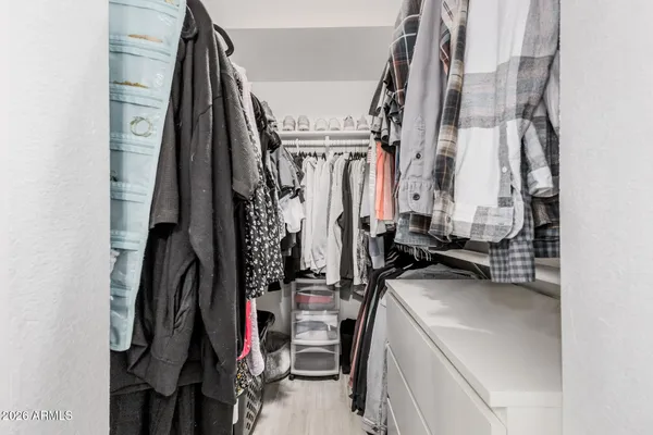 a view of walk in closet with clothes and shoes