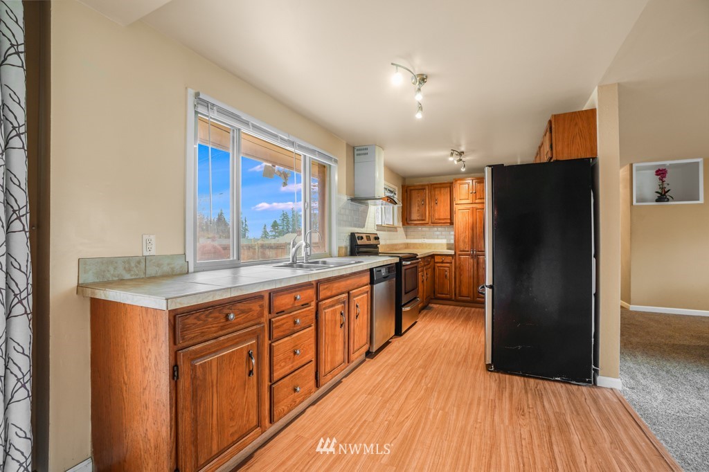 3601 Northeast 9th Street Renton, WA 98056 - Photo 11 of 23 a kitchen with stainless steel appliances granite countertop a refrigerator a sink dishwasher a stove with wooden floor and cabinets