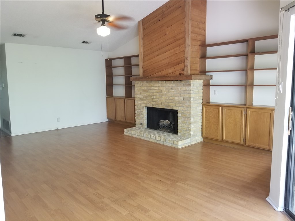 a view of an empty room with a fireplace and a window