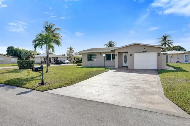 a front view of a house with a yard and palm trees