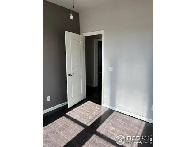 a view of an empty room with wooden floor and cabinets