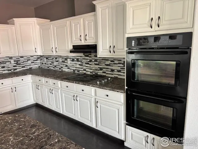 a kitchen with granite countertop white cabinets and appliances