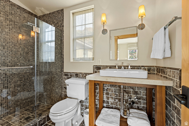 105 River Bend Circle, Unit 105 Springdale, UT 84767 - Photo 32 of 56 Bathroom featuring a glass-enclosed shower with mosaic tile surround, a single window, a vanity with an undermount sink, and wall-mounted sconces