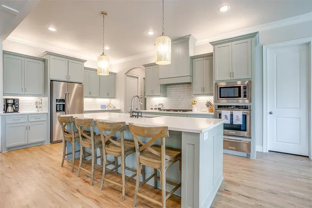 a kitchen with stainless steel appliances kitchen island granite countertop a refrigerator and a stove top oven