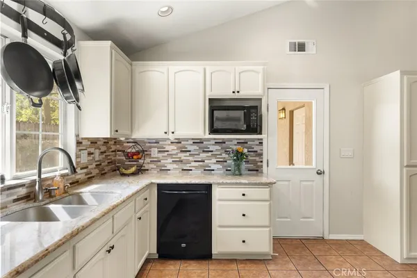 a kitchen with white cabinets a sink and appliances