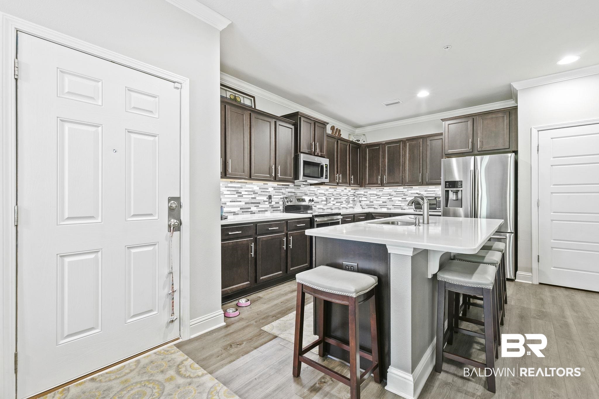 6867 Spaniel Drive, Unit B Daphne, AL 36527 - Photo 9 of 36 Kitchen with a breakfast bar, appliances with stainless steel finishes, a center island with sink, and dark brown cabinets