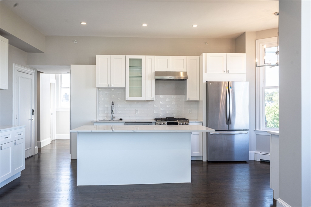 85 Regent Street, Unit 8 Boston, MA 02119 - Photo 15 of 30 a kitchen with stainless steel appliances granite countertop a refrigerator a sink a stove and white cabinets with wooden floor