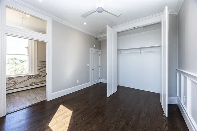an empty room with wooden floor cabinet and windows