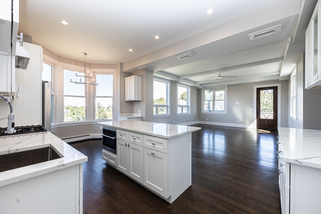 85 Regent Street, Unit 8 Boston, MA 02119 - Photo 2 of 30 a kitchen with a stove a sink a dining table and chairs