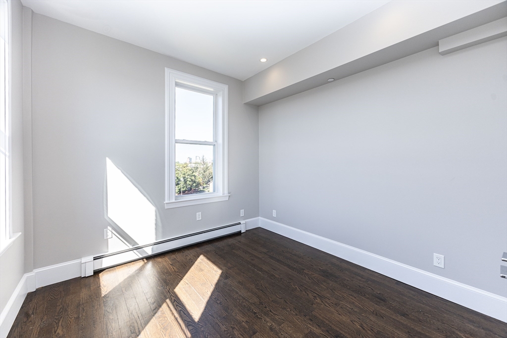 85 Regent Street, Unit 8 Boston, MA 02119 - Photo 22 of 30 a view of an empty room with wooden floor and a window