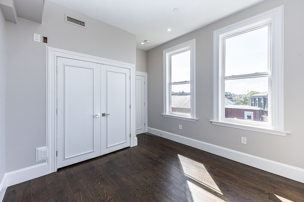 85 Regent Street, Unit 8 Boston, MA 02119 - Photo 24 of 30 a view of an empty room with wooden floor and a window