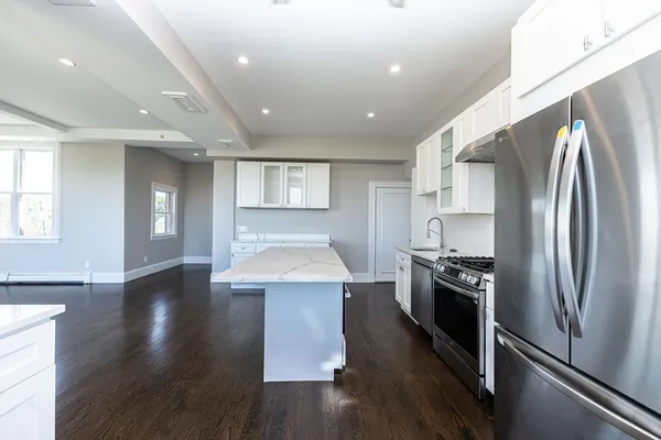 a kitchen with kitchen island stainless steel appliances a stove refrigerator sink and cabinets