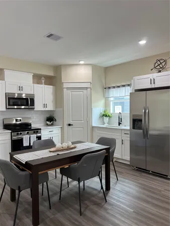 a kitchen with a table chairs refrigerator and cabinets
