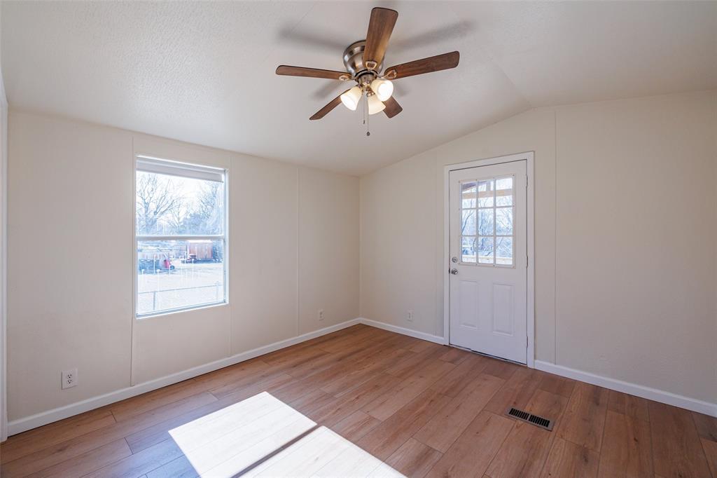 720 Jupiter Avenue Granbury, TX 76049 - Photo 18 of 23 an empty room with wooden floor chandelier fan and windows