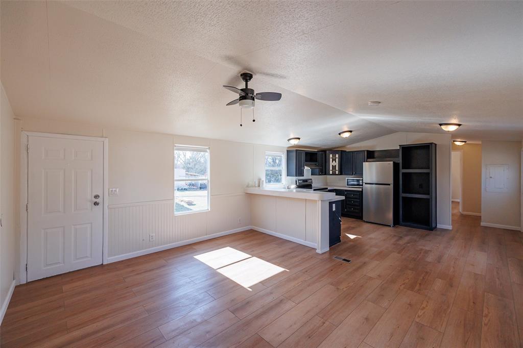 720 Jupiter Avenue Granbury, TX 76049 - Photo 4 of 23 a large kitchen with kitchen island a sink dishwasher a stove and a refrigerator with wooden floor
