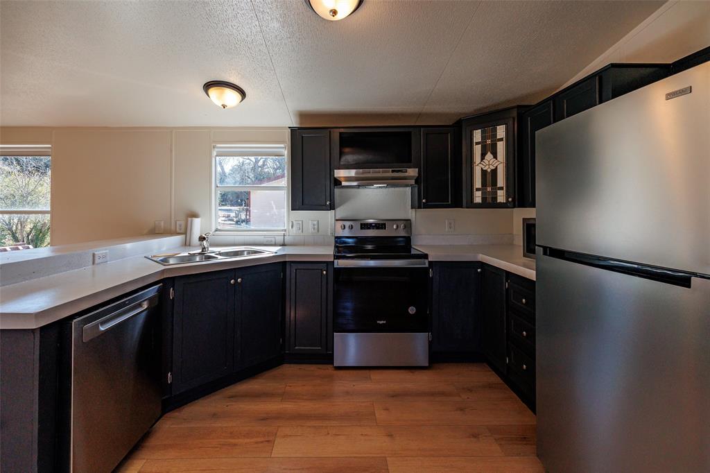 720 Jupiter Avenue Granbury, TX 76049 - Photo 8 of 23 a kitchen with a refrigerator and a sink