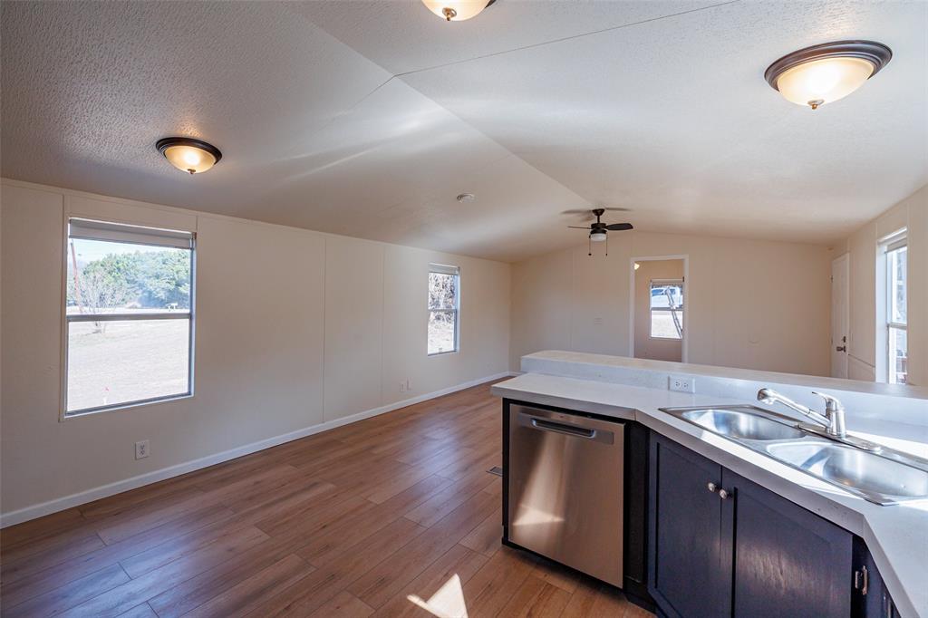 720 Jupiter Avenue Granbury, TX 76049 - Photo 9 of 23 a kitchen with kitchen island a sink wooden floor and a large window