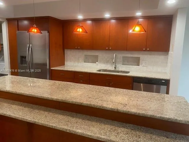 a kitchen with stainless steel appliances granite countertop a sink and a refrigerator