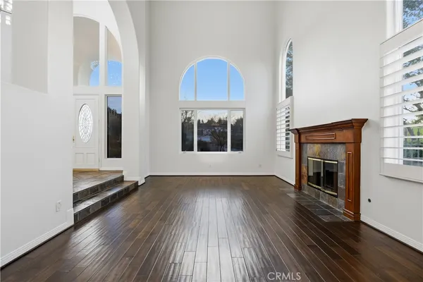 an empty room with wooden floor fireplace and windows