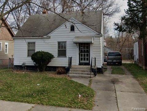 9574 Cheyenne Street Detroit, MI 48227 - Photo 1 of 2 White siding exterior with a pitched roof, front entry with storm door, concrete steps, and a driveway extending along the side