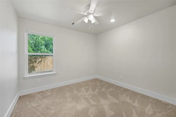 an empty room with a window and a fan