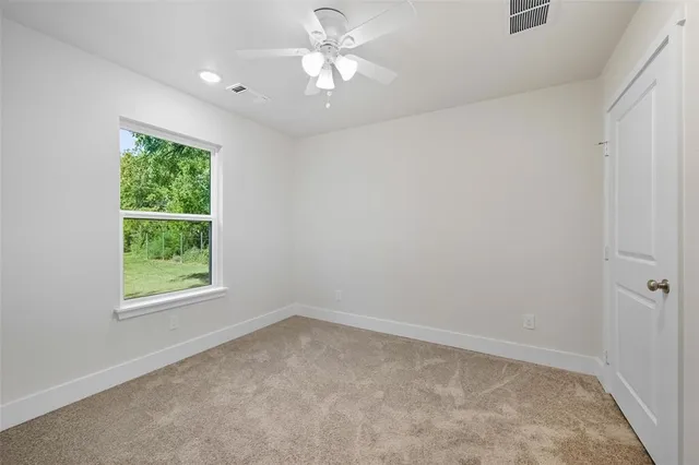 an empty room with a window and a fan