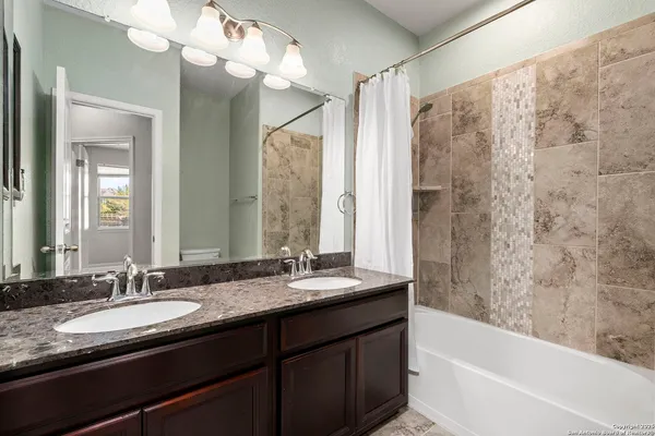 a bathroom with a granite countertop sink mirror and a bathtub