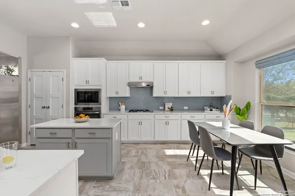 a kitchen with kitchen island granite countertop a table chairs microwave and cabinets