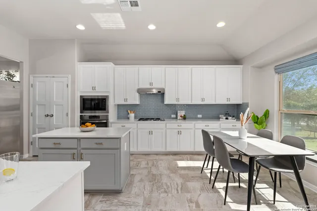 a kitchen with kitchen island granite countertop a table chairs microwave and cabinets