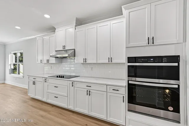 a kitchen with stainless steel appliances granite countertop a stove and white cabinets with wooden floor