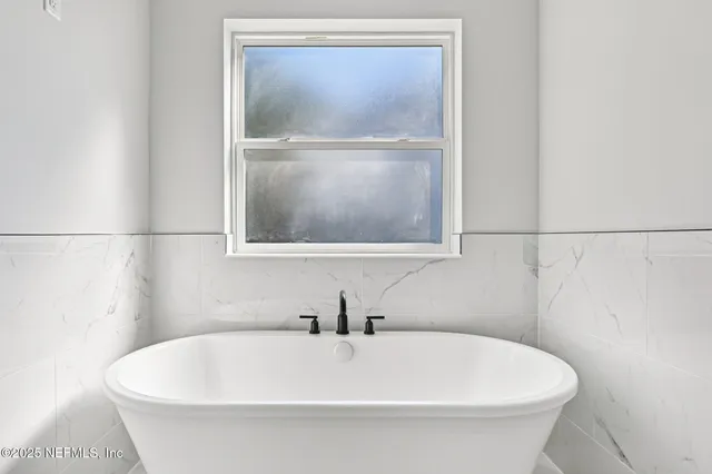 a bathroom with a tub sink a shower and a mirror