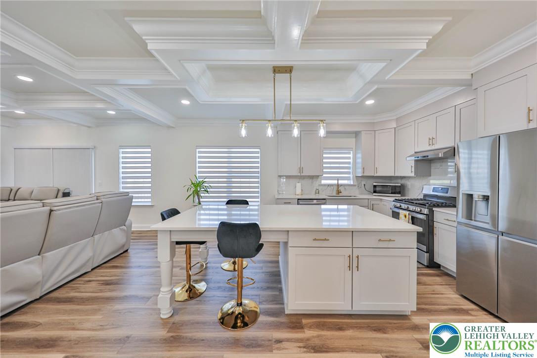 1105 Meco Road Easton, PA 18040 - Photo 23 of 100 Ornate coffered ceilings crown a modern open-concept space featuring a large central island.