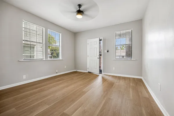 an empty room with wooden floor and windows