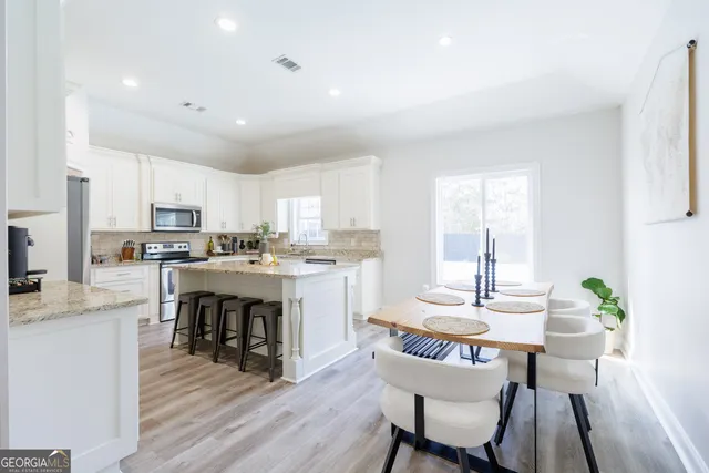 a kitchen with stainless steel appliances granite countertop a stove a sink dishwasher and white cabinets with wooden floor