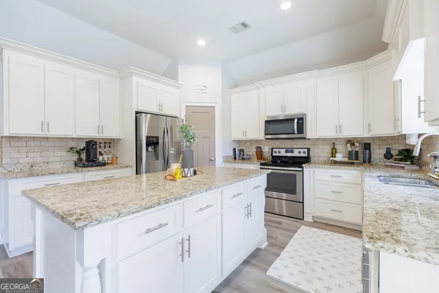 a kitchen with granite countertop a sink a counter top space appliances and cabinets