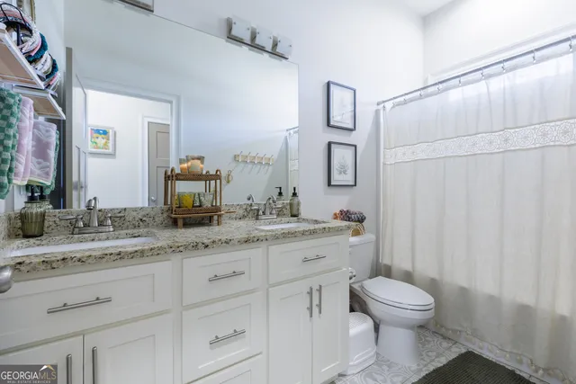 a bathroom with a granite countertop toilet sink and mirror