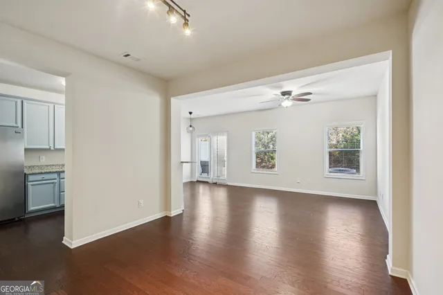 a view of an empty room with wooden floor and a window