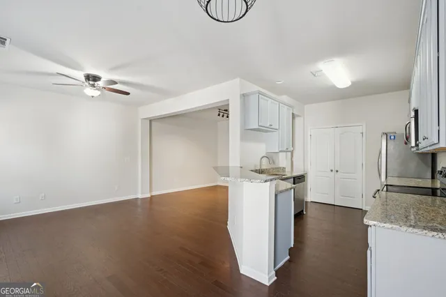 a kitchen with stainless steel appliances granite countertop a refrigerator a stove a sink and white cabinets