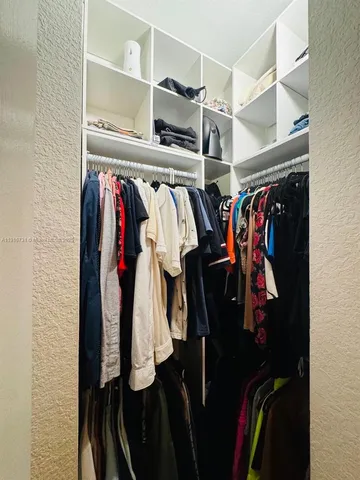 a view of walk in closet with clothes and shoes