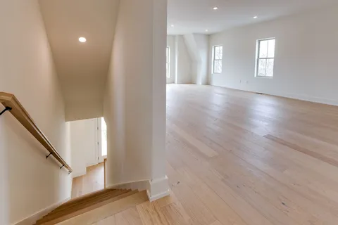 a view of a hallway with wooden floor and staircase