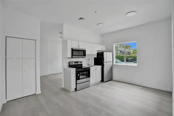 a kitchen with stainless steel appliances a white refrigerator a stove a microwave and a refrigerator