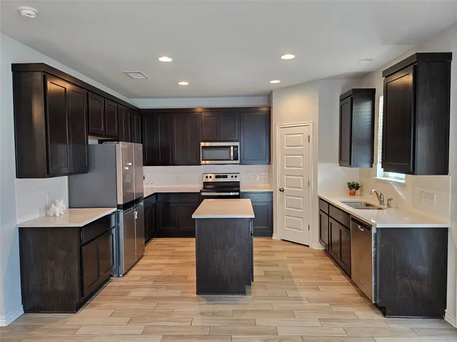 a large kitchen with stainless steel appliances kitchen island granite countertop a stove and a refrigerator
