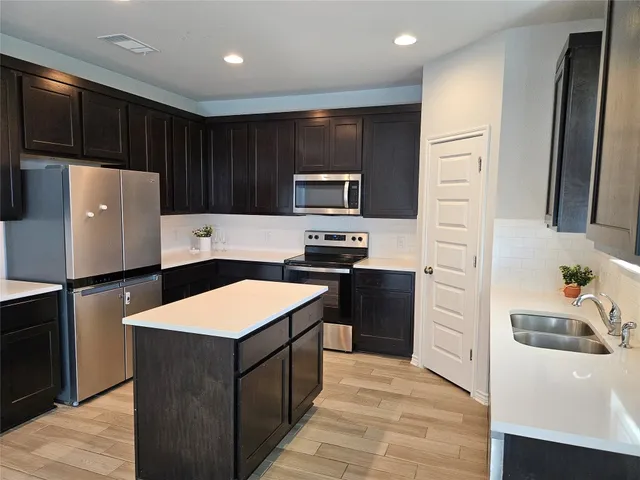 a kitchen with granite countertop a refrigerator and a stove top oven