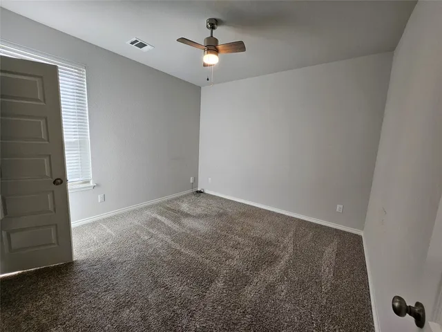 an empty room with a ceiling fan and a window