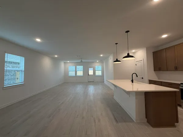 a large kitchen with kitchen island a sink dishwasher a stove and a refrigerator with wooden floor