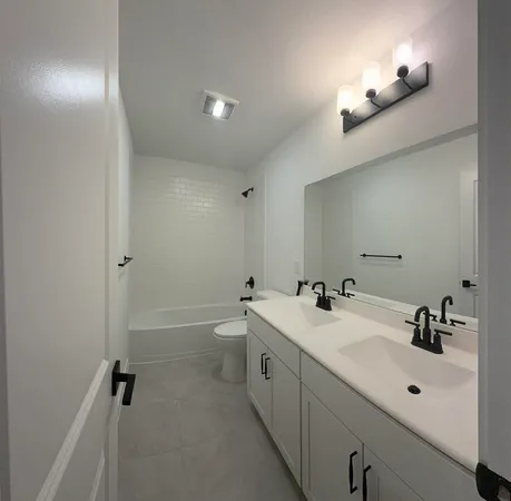 a bathroom with a double vanity sink toilet and a tub